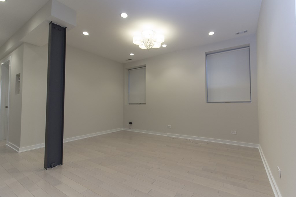 a large empty living room with a ceiling light and windows