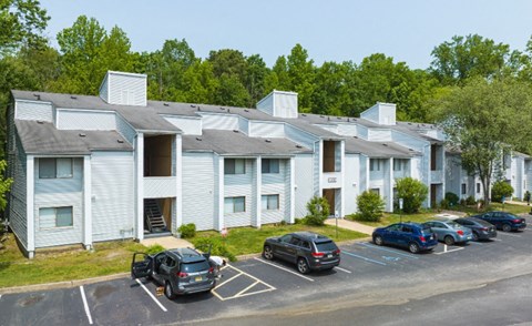 A parking lot in front of a building with cars parked.
