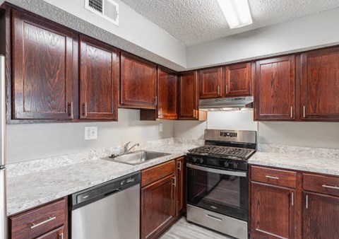 A kitchen with wooden cabinets and a stainless steel dishwasher.