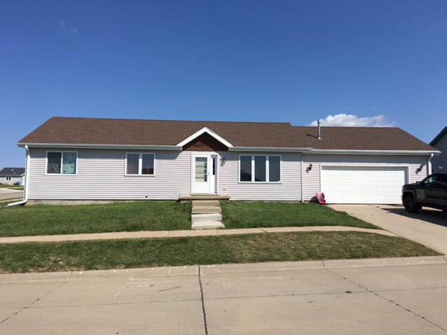 a white house with a brown roof on a lawn
