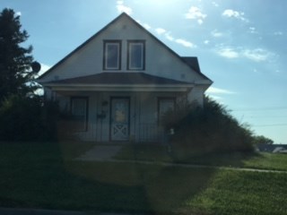 the front of a white house with a lawn and a blue sky