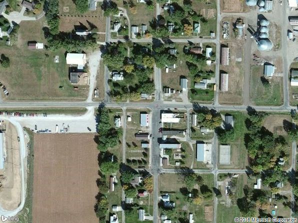A satellite image of a residential area with houses and a large open field.