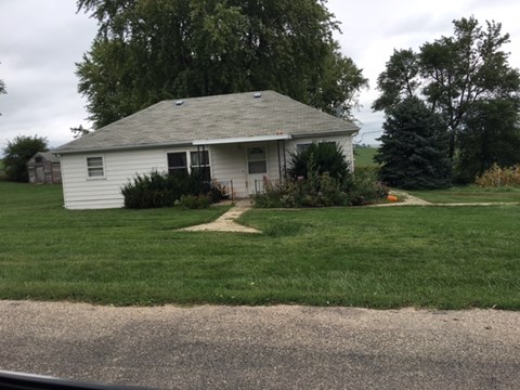 A white house with a grey roof and a small garden in front.