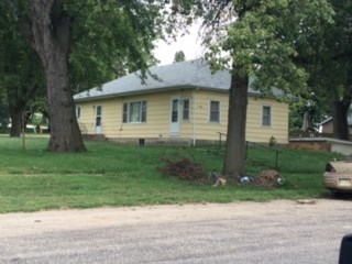 a yellow house with trees and grass in front of it