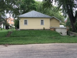 a yellow house on a hill with a road and trees