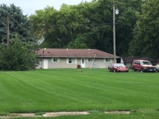 a house with cars parked in a field