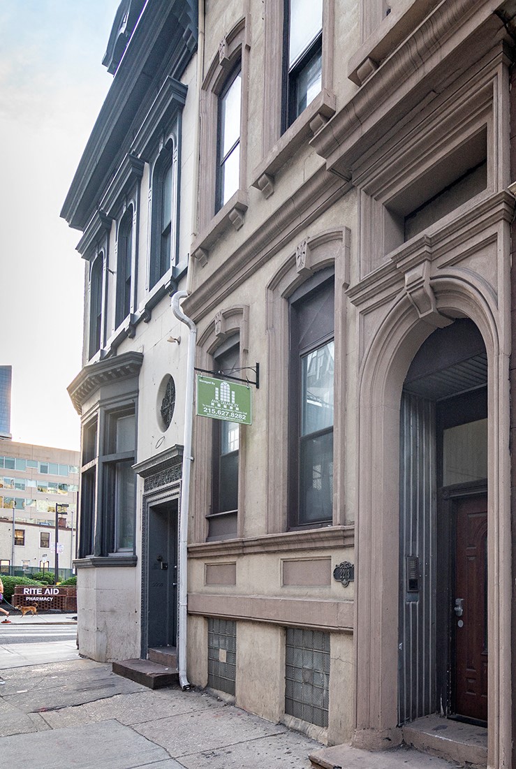 an old building with a green sign on it on a street