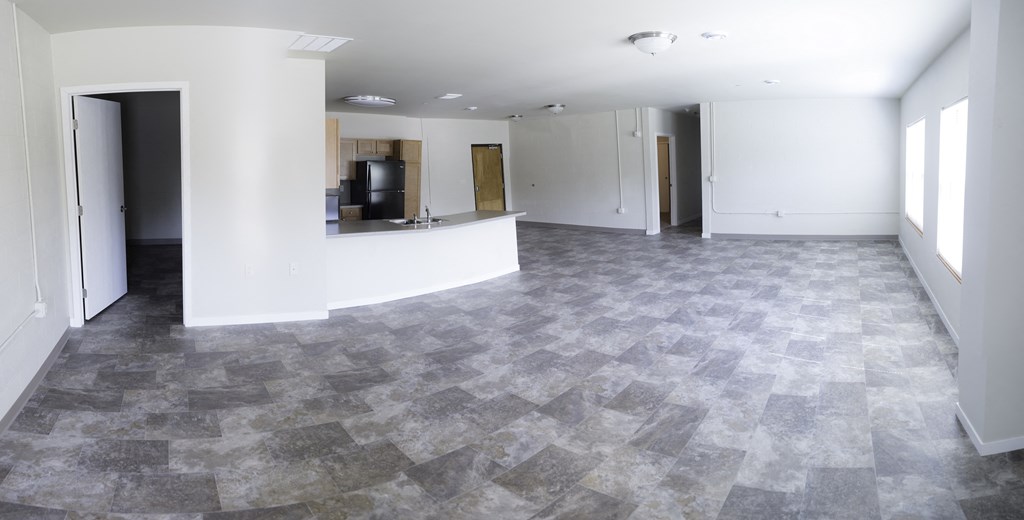 an empty living room with a counter and a kitchen