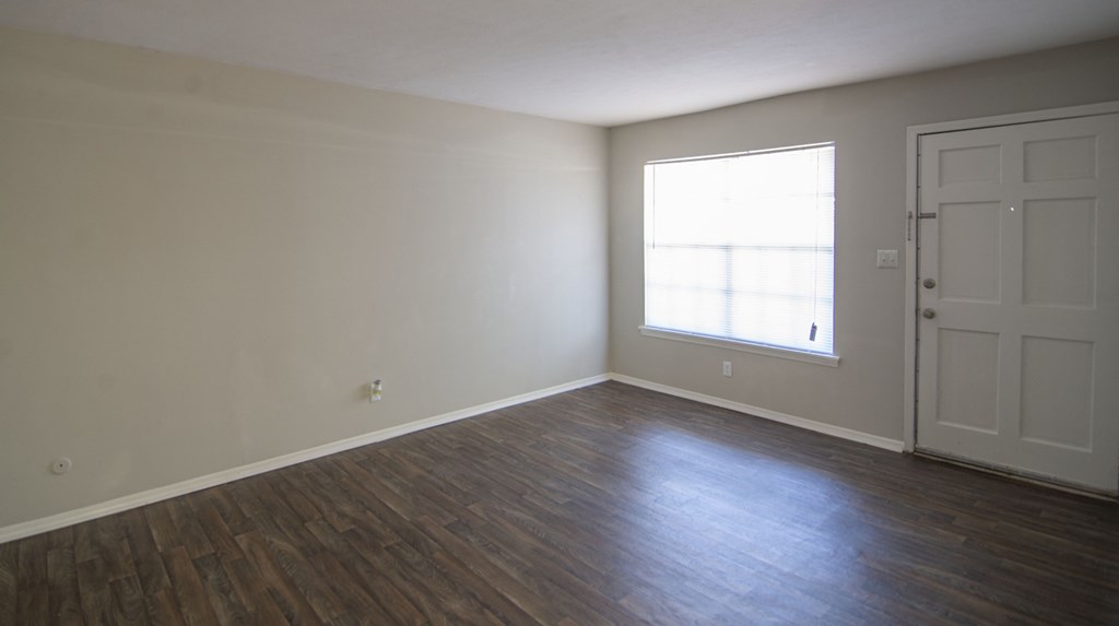 an empty living room with wood floors and a window