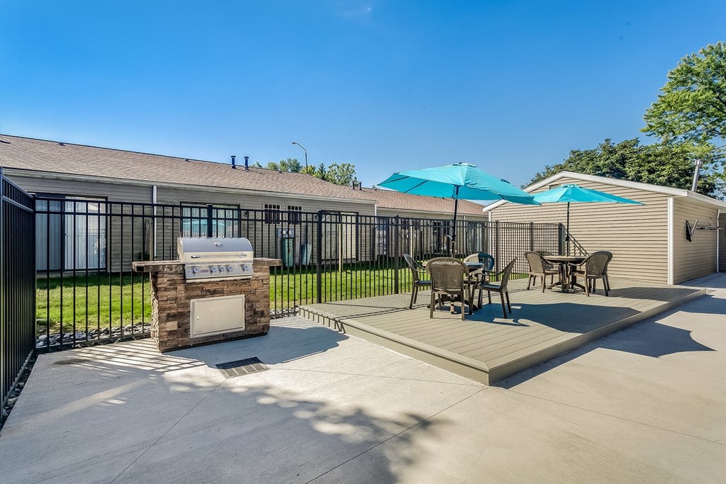 a patio with a grill and tables with umbrellas