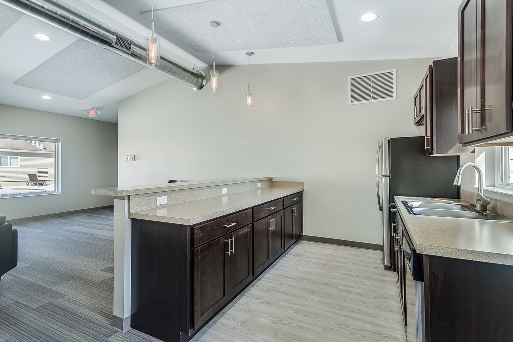 an empty kitchen with wooden cabinets and a stainless steel refrigerator