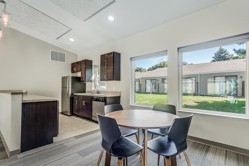 a dining area with a table and chairs and a kitchen with a large window