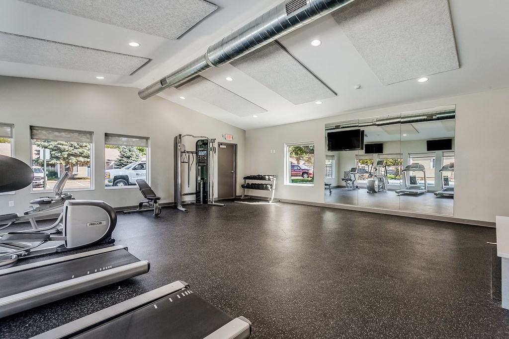 a gym with treadmills and other exercise equipment and a large window