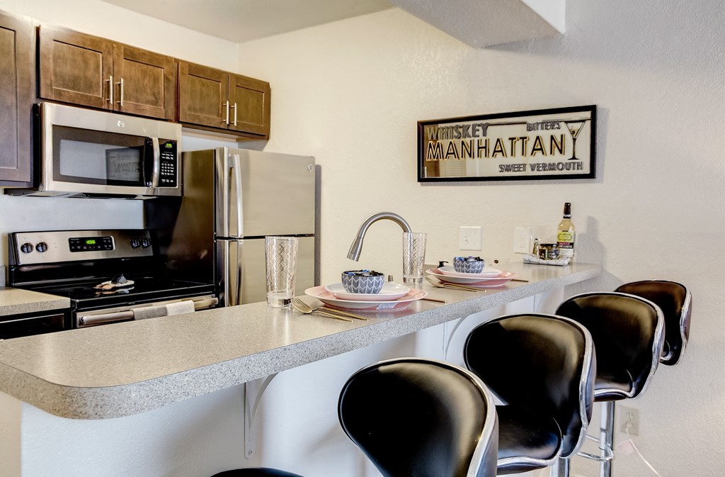 a kitchen with a counter with chairs and a sink and a refrigerator