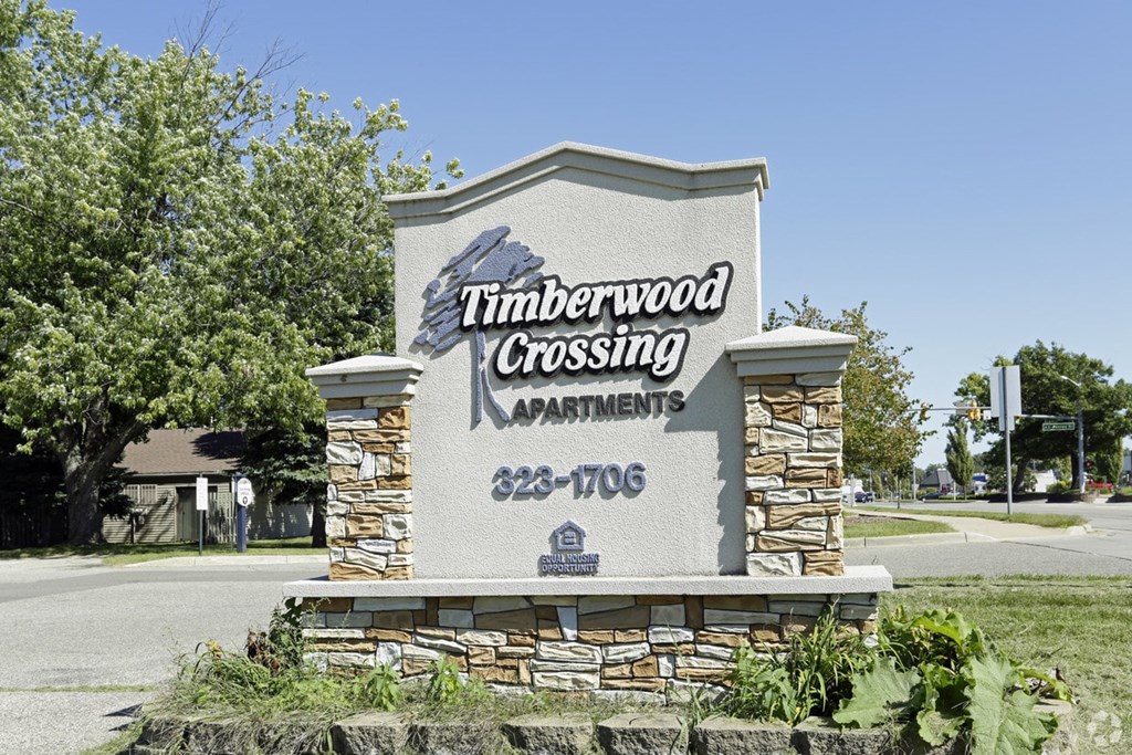 a sign for timbrewood crossing apartments on the side of a road