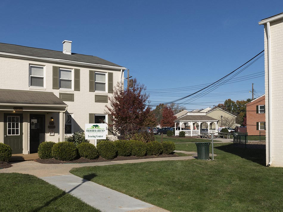 an apartment building with a yard and a sign in front of it
