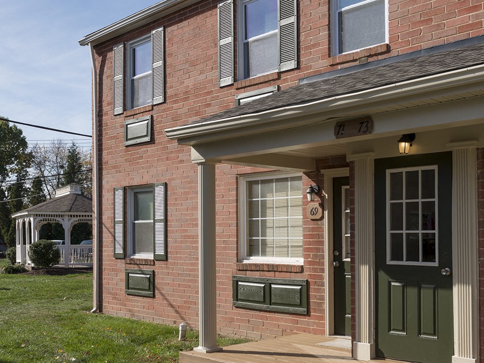 a brick house with a porch and a green door