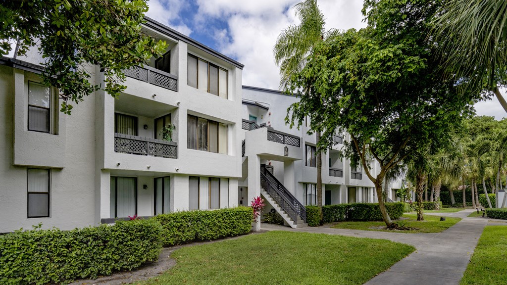 a row of white apartment buildings with grass and trees