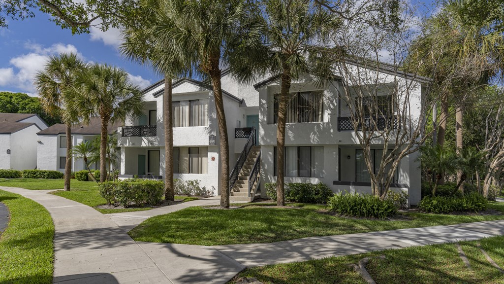 a white house with palm trees and a sidewalk