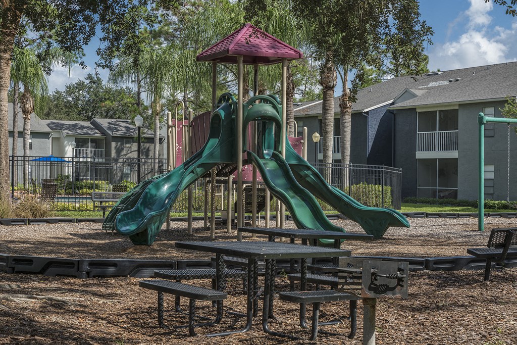 a playground with a slide and picnic tables