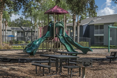 a playground with a slide and picnic tables