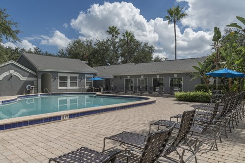 a swimming pool with chairs and a building in the background