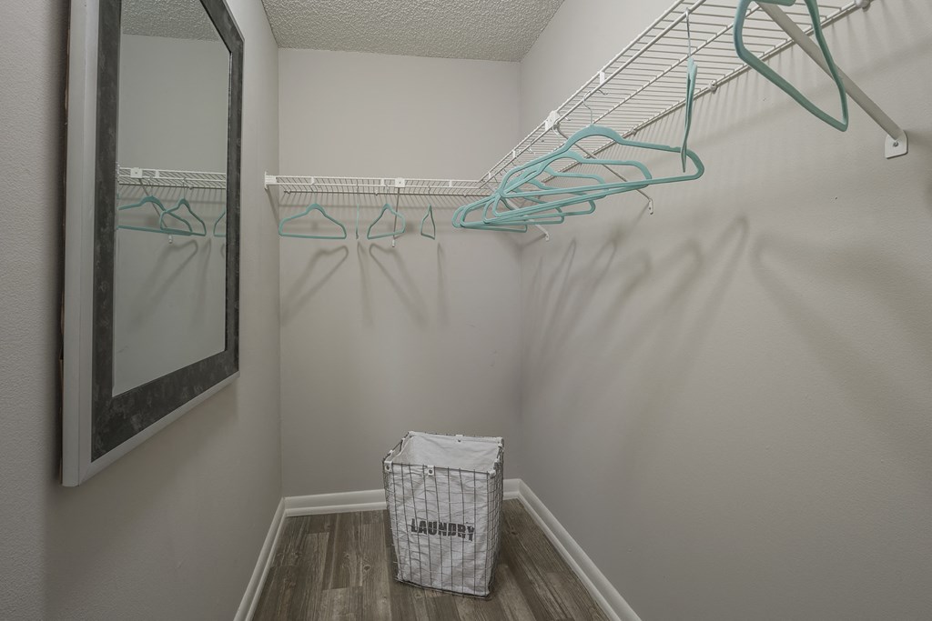 a closet with hooks and a mirror in the corner of a room