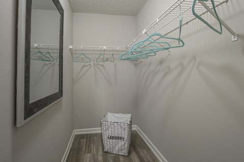 a closet with hooks and a mirror in the corner of a room