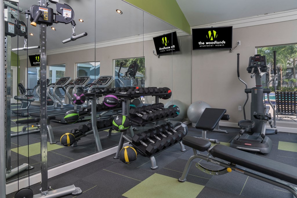 a gym with weights and cardio equipment in a building with windows