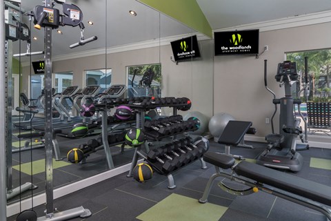 a gym with weights and cardio equipment in a building with windows