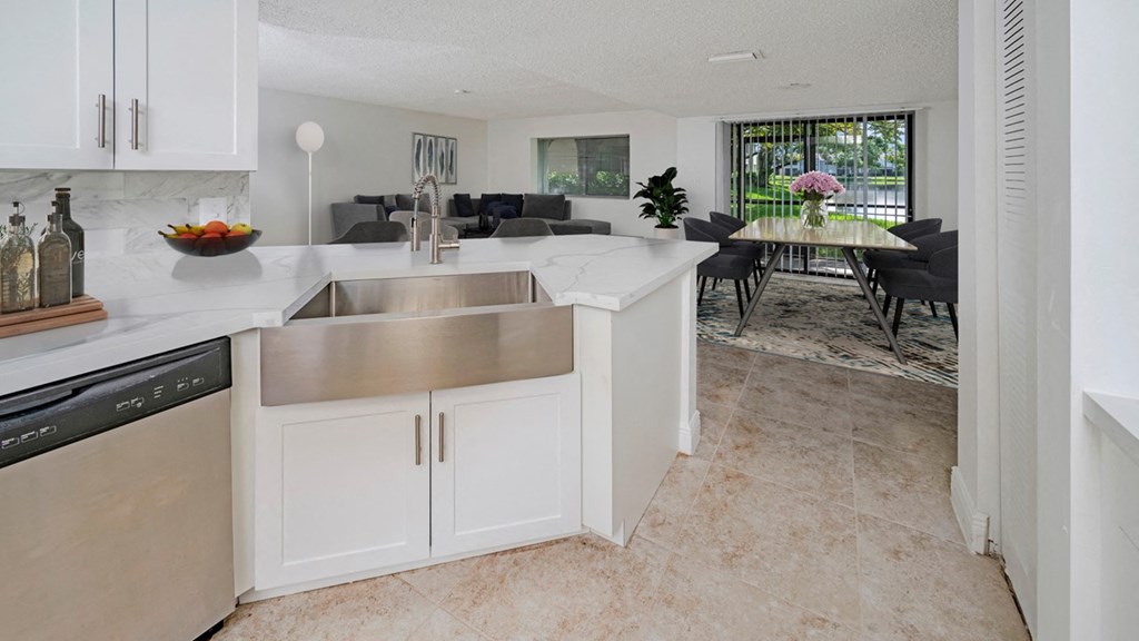 a white kitchen with stainless steel appliances and a dining room table