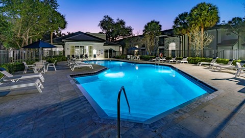 A swimming pool surrounded by lounge chairs and trees.