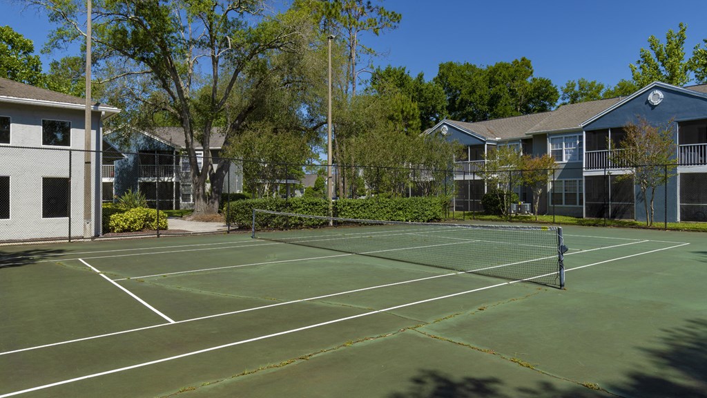 a tennis court with apartments in the background