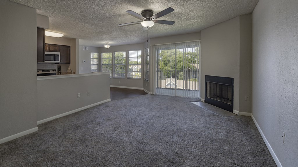 an empty living room with a fireplace and a ceiling fan