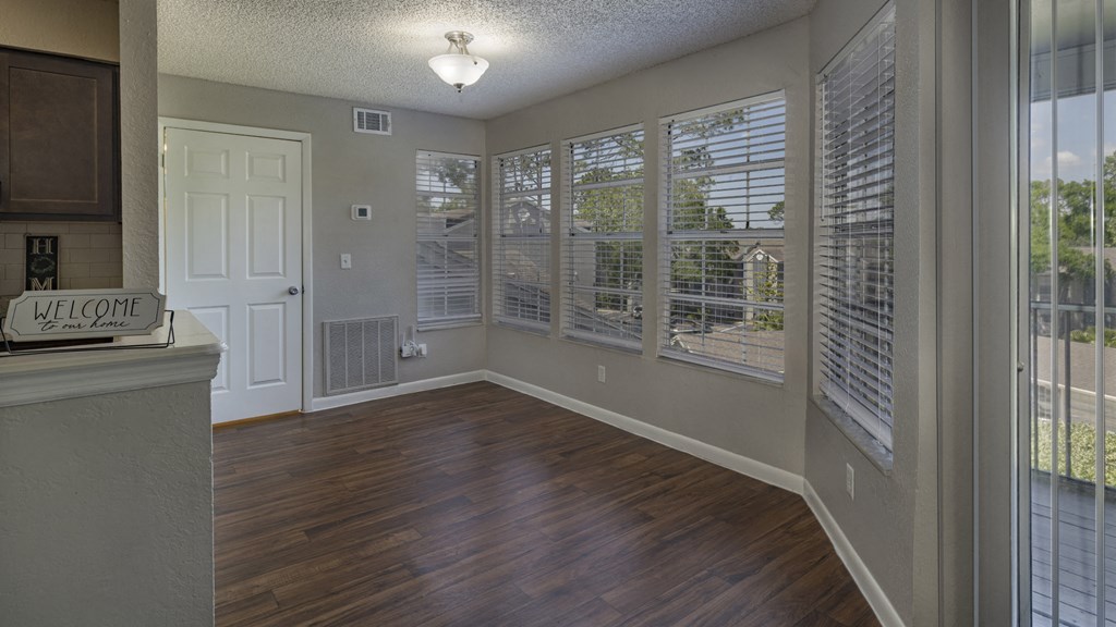 an empty living room with large windows and wood flooring