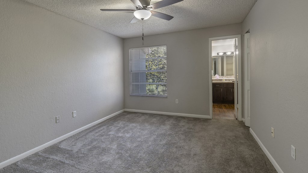 an empty living room with a ceiling fan and a window
