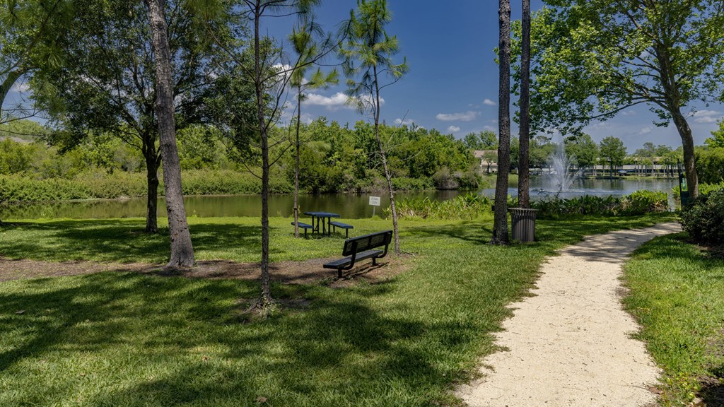 a park with a path and benches next to a lake