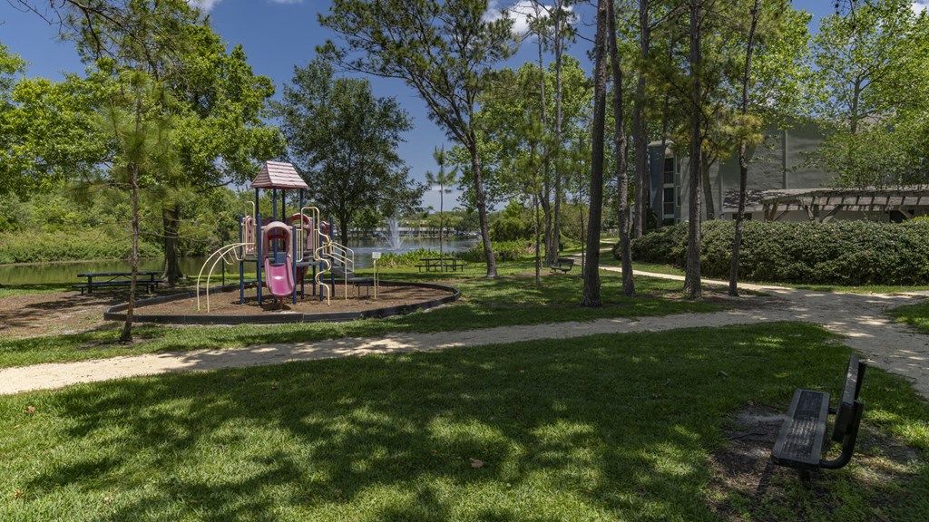 a playground in a park with trees and a building in the background