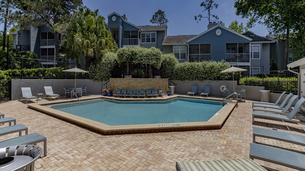 a swimming pool with chairs and umbrellas in front of a building