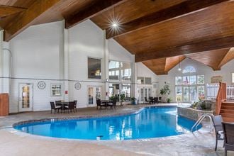 the indoor pool is surrounded by chairs and a wooden ceiling
