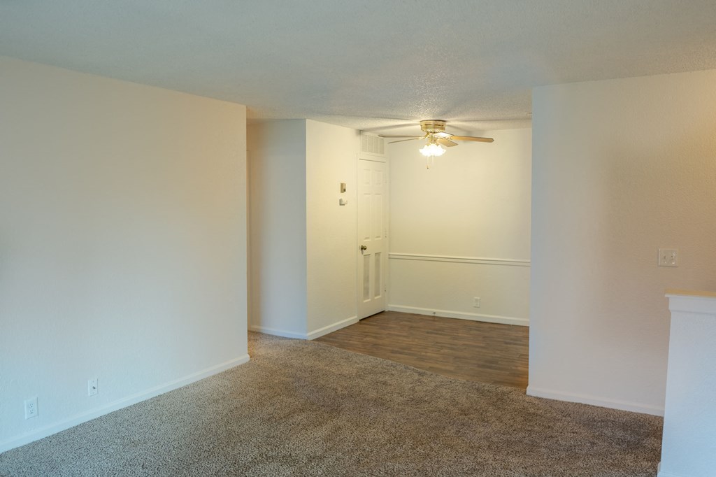 an empty living room with white walls and a ceiling fan