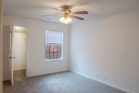 Omaha, NE, Apartments Near Vintage Pointe - Apple Creek Apartments - Bedroom With Carpet Flooring, Ceiling Fan Lighting, Open Closet Entry, and Window With Blinds.