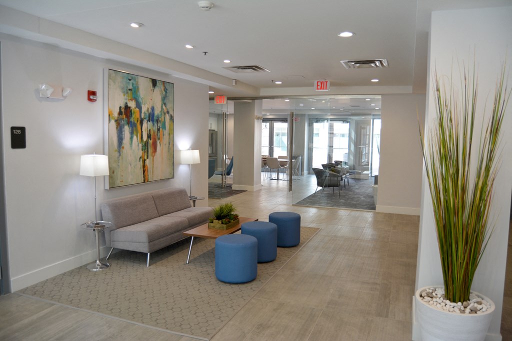 a lobby with couches and stools and a painting on the wall