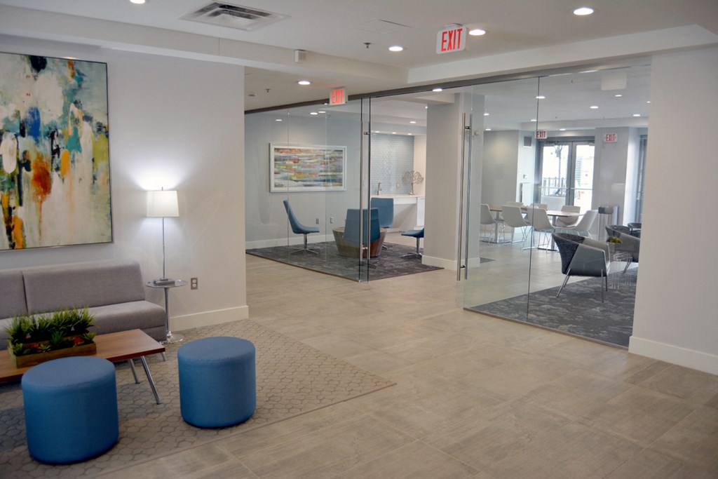 a large lobby with chairs and tables and an exit sign