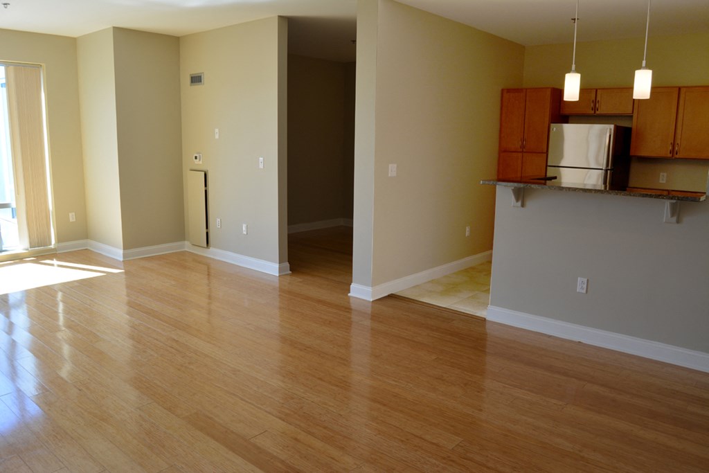 an empty living room with wood floors and a kitchen