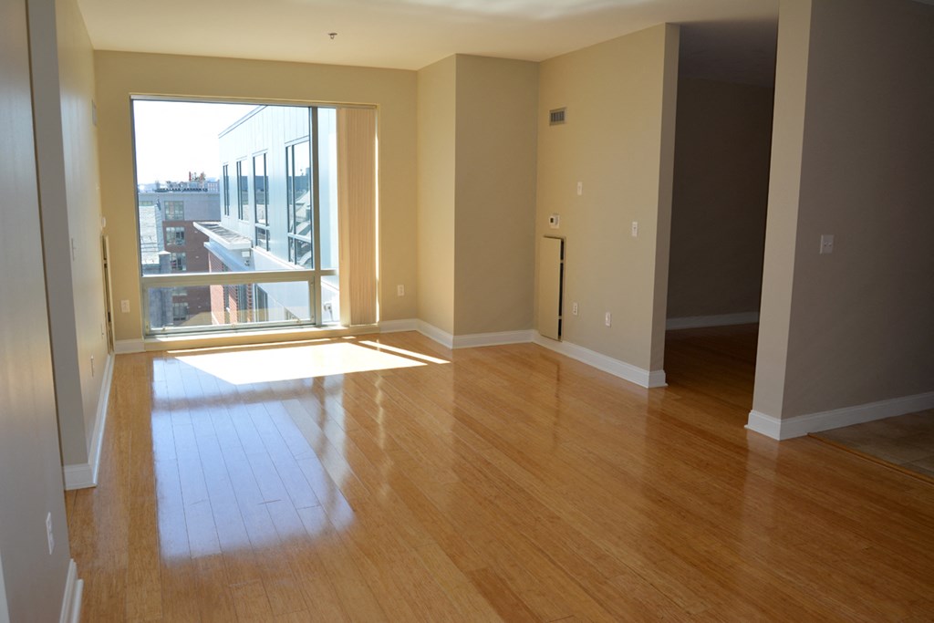 an empty living room with wood floors and a window