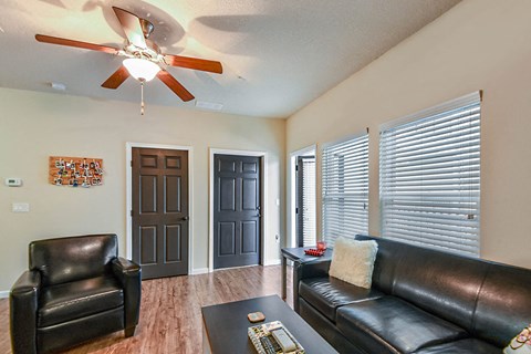 a living room with leather furniture and a ceiling fan