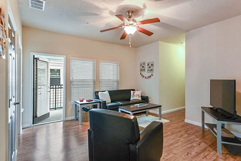 a living room with leather furniture and a ceiling fan