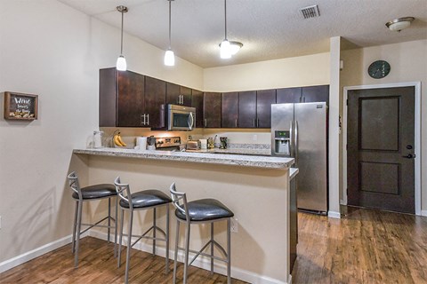 a kitchen with a bar with three stools