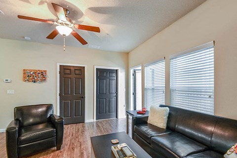 a living room with leather furniture and a ceiling fan